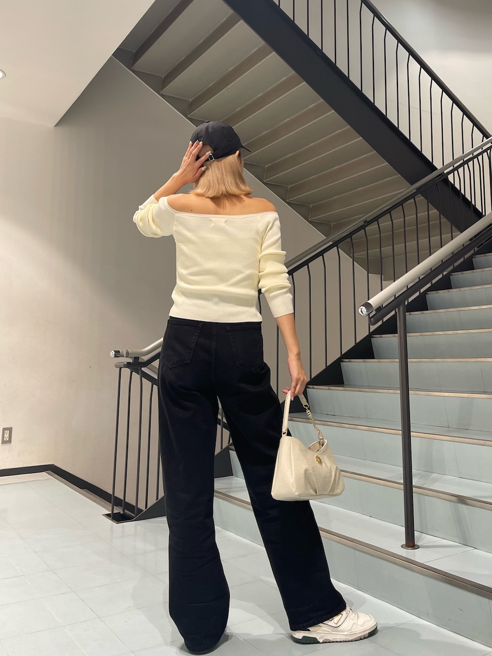 ホワイト系のニット/セーター、ブラック系のデニムパンツ、ホワイト系のハンドバッグを着用したレディースの夏コーディネートの6枚目の写真