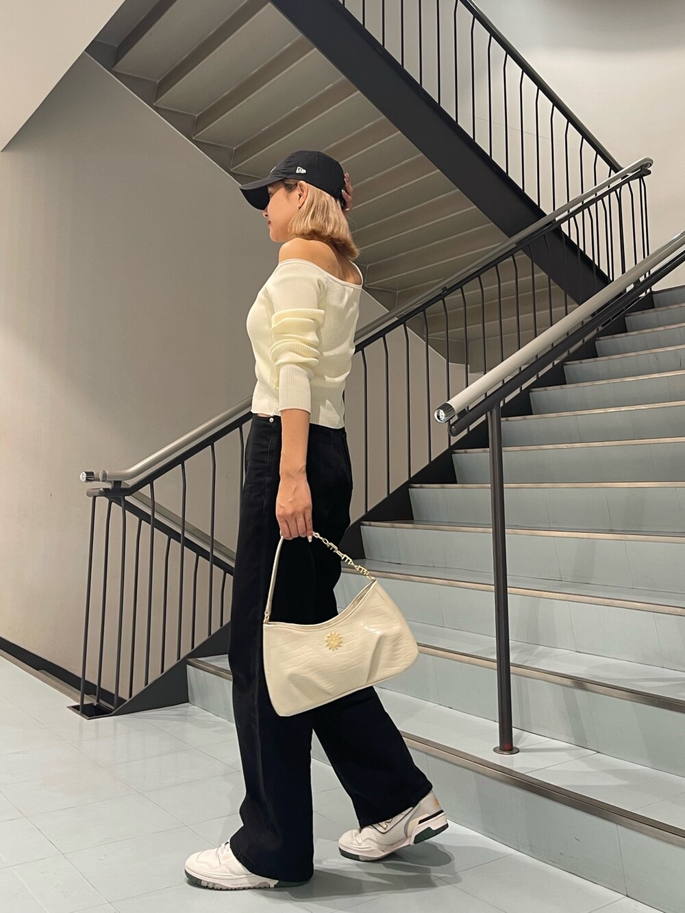 ホワイト系のニット/セーター、ブラック系のデニムパンツ、ホワイト系のハンドバッグを着用したレディースの夏コーディネートの4枚目の写真