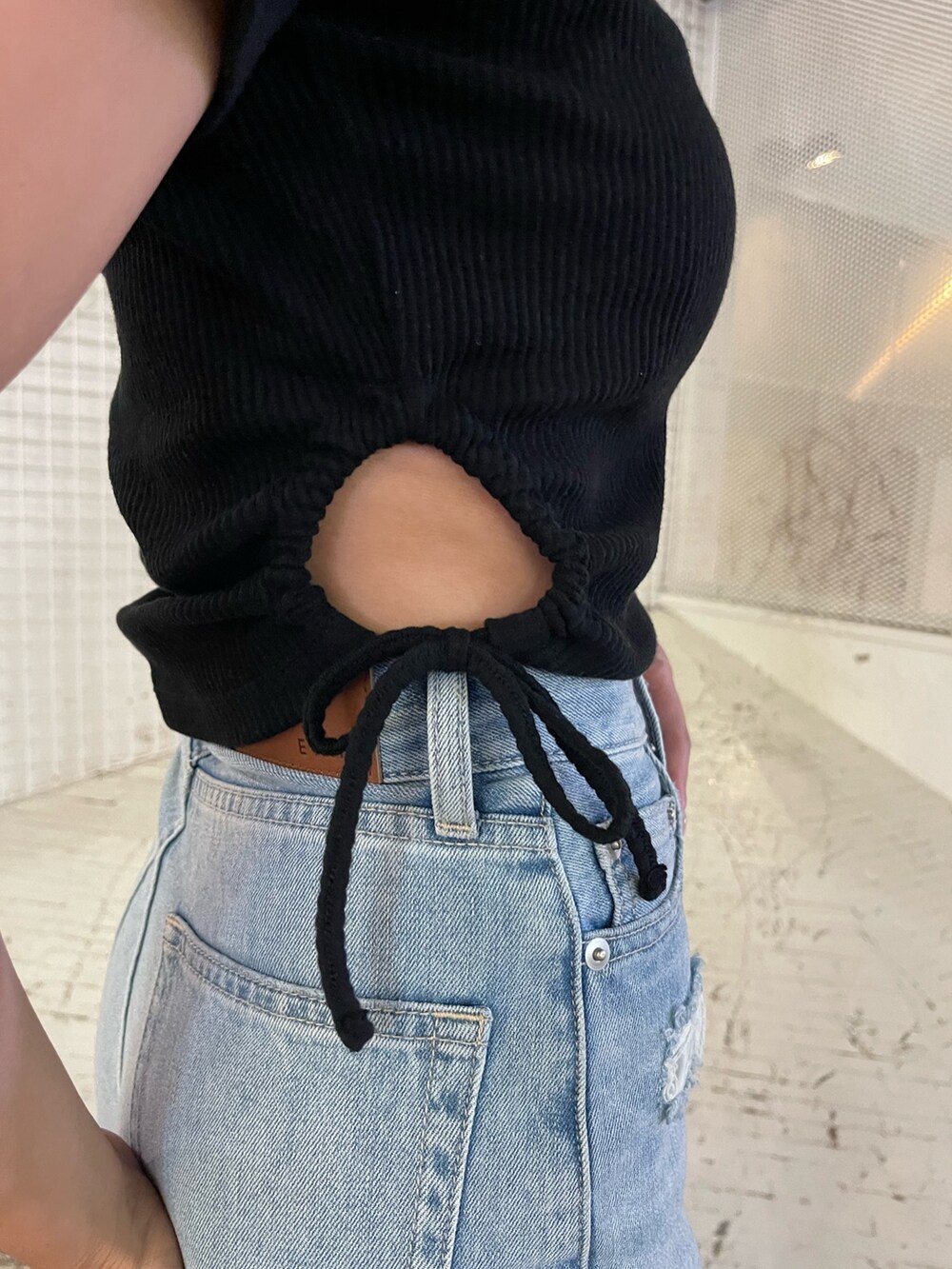 ブルー系のデニムパンツ、ブラック系のTシャツ/カットソー、ブラック系のサンダルを着用したレディースの夏コーディネートの7枚目の写真