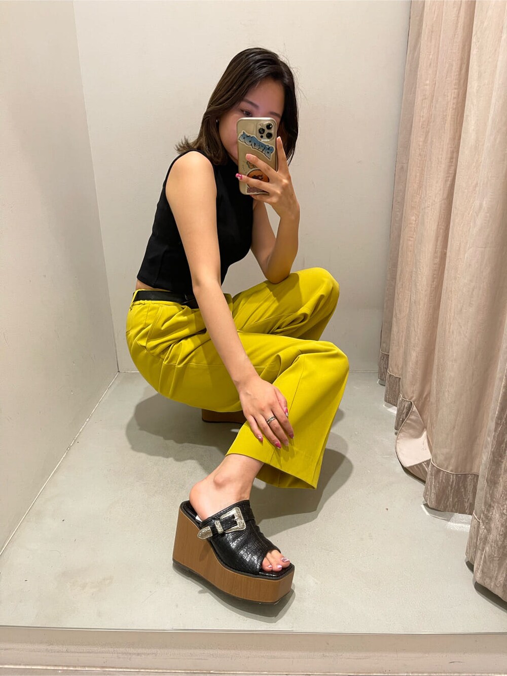 イエロー系のスラックス、ブラック系のタンクトップ、ブラック系のサンダルを着用したレディースの春コーディネートの6枚目の写真