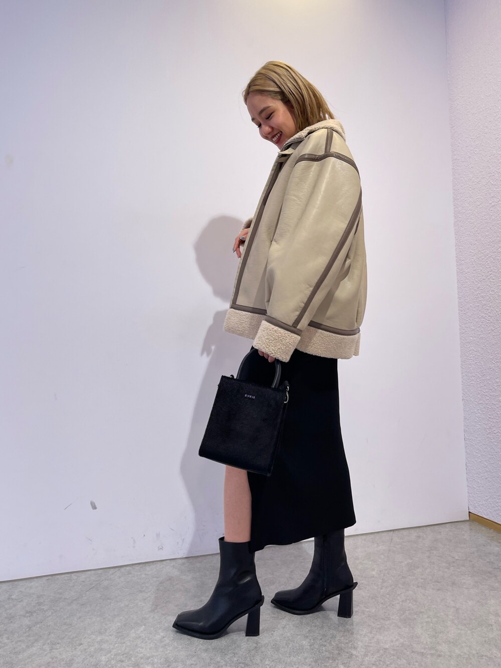 ブラック系のブーツ、ブラック系のショルダーバッグ、ブラック系のワンピースを着用したレディースの冬コーディネートの2枚目の写真