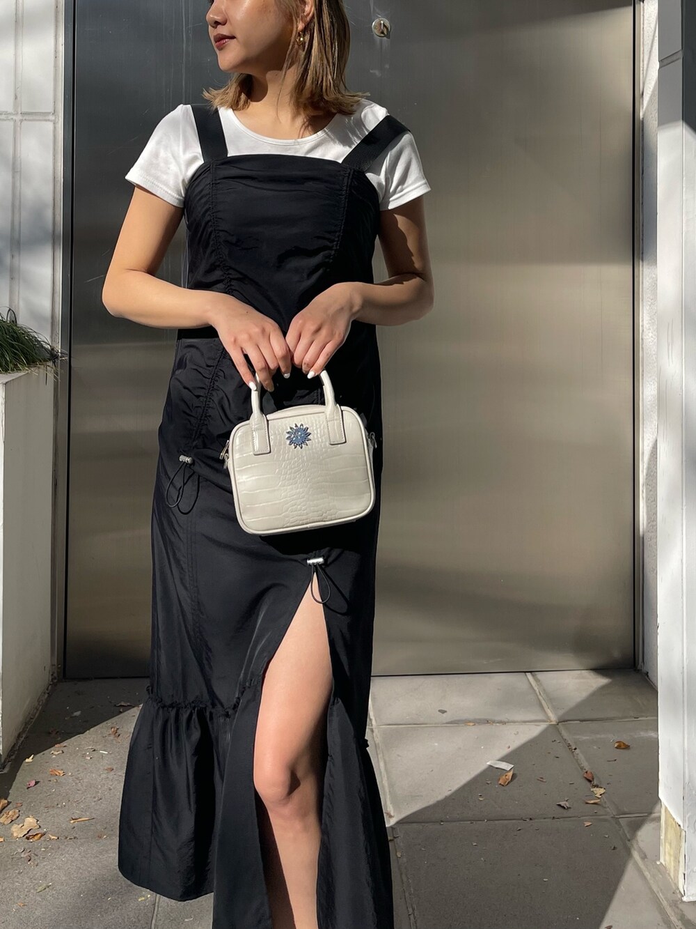 ブラック系のワンピース、ホワイト系のショルダーバッグ、ブラック系のブーツを着用したレディースの冬コーディネートの3枚目の写真