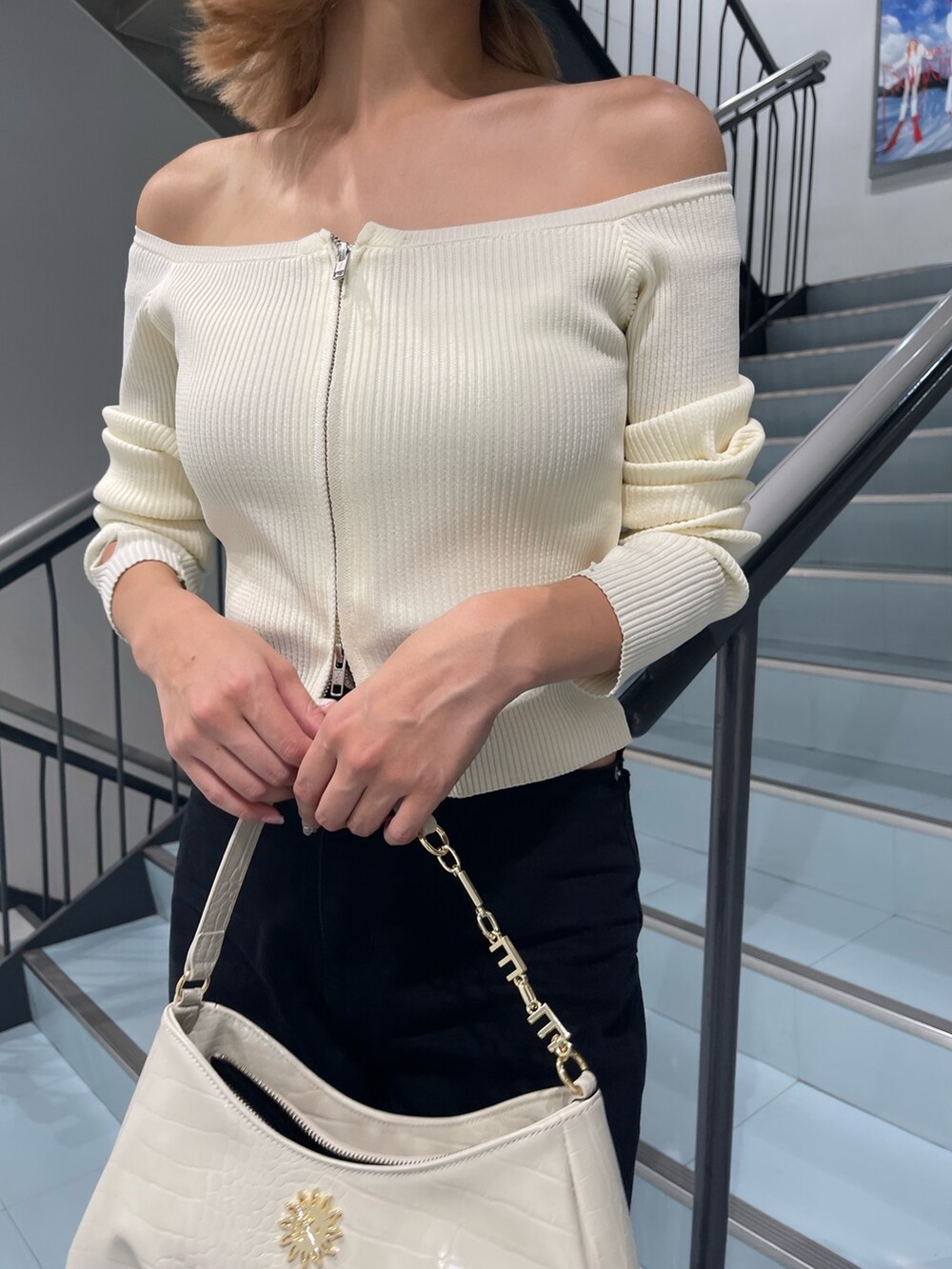 ホワイト系のニット/セーター、ブラック系のデニムパンツ、ホワイト系のハンドバッグを着用したレディースの夏コーディネートの8枚目の写真