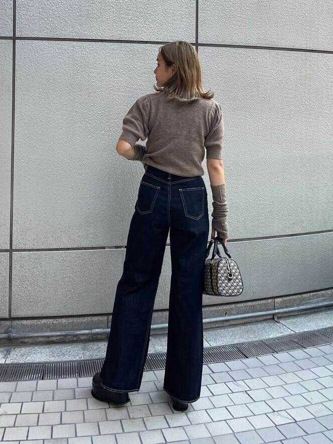 ブラック系のスリッポン、ブラック系のボストンバッグ、ブルー系のデニムパンツを着用したレディースの夏コーディネートの3枚目の写真