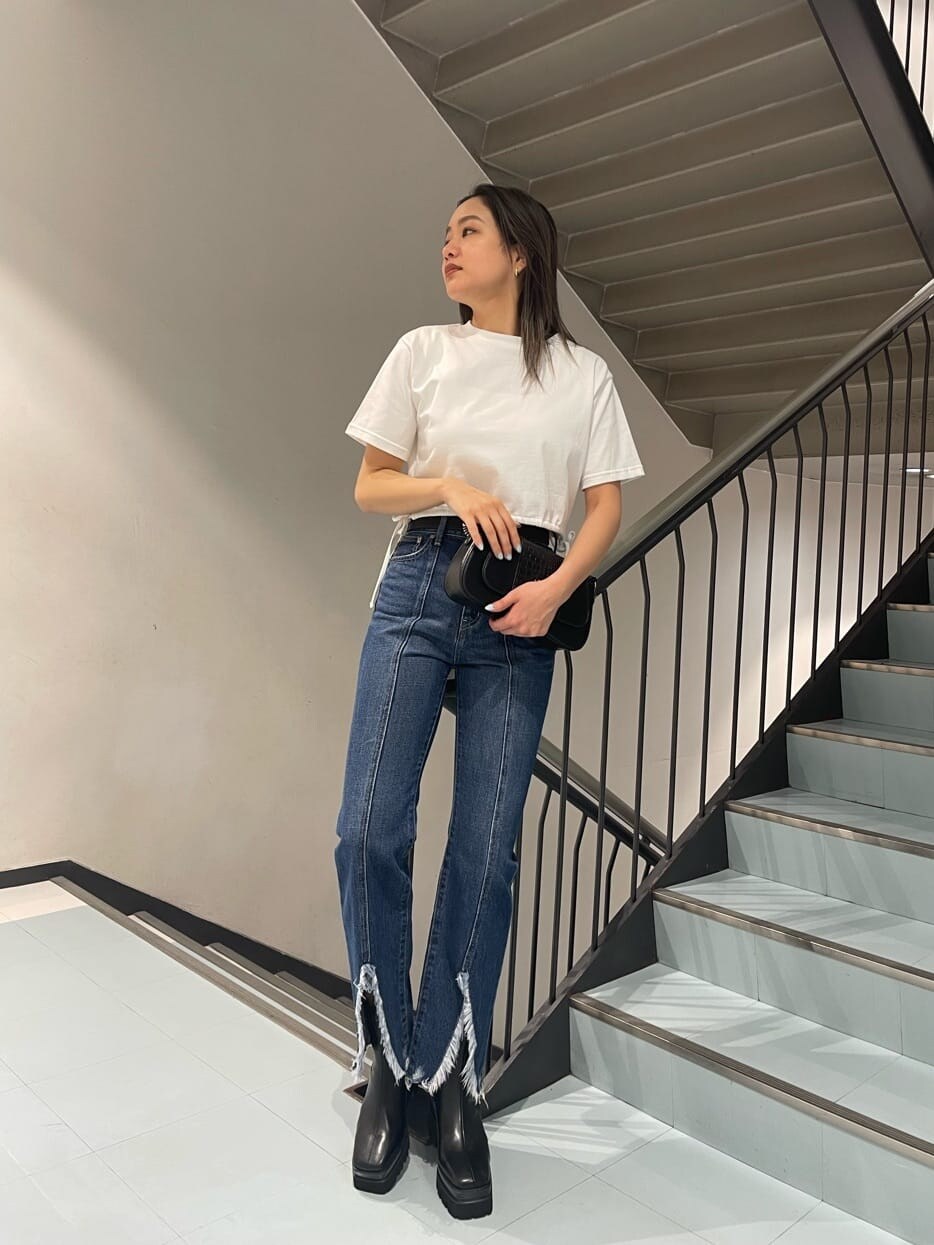 ホワイト系のTシャツ/カットソー、ブラック系のブーツ、ブルー系のデニムパンツを着用したレディースの春コーディネートの2枚目の写真