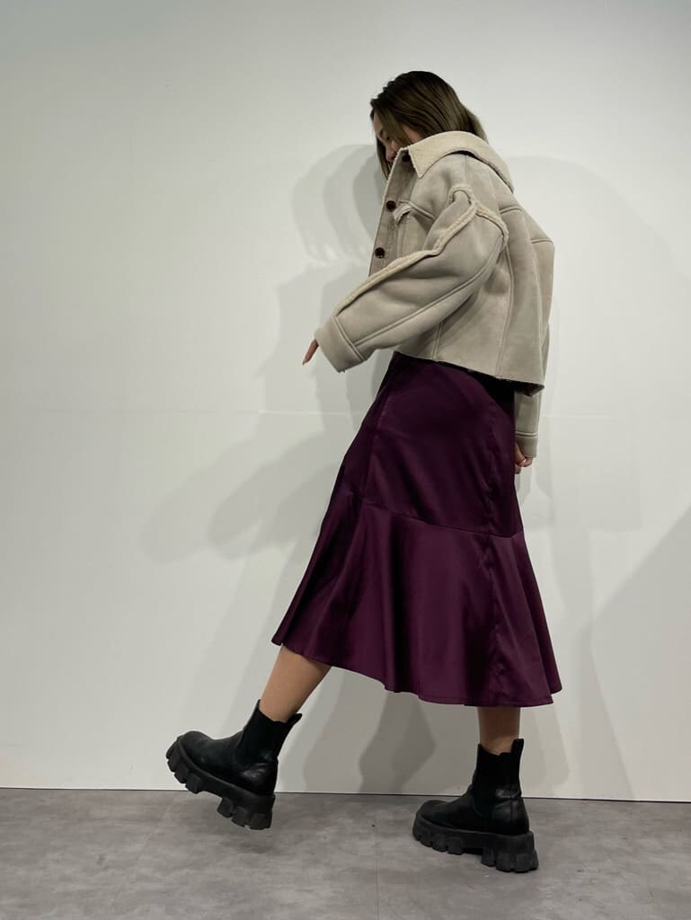 ブラック系のブーツ、ホワイト系のニット/セーター、パープル系のスカートを着用したレディースの秋コーディネートの3枚目の写真