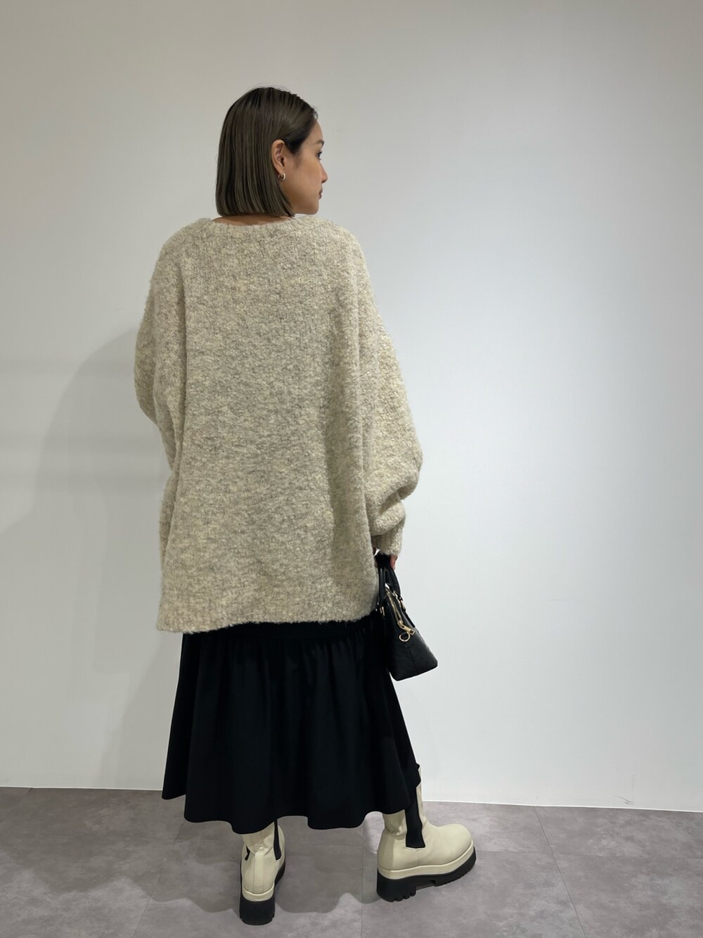 ブラック系のスカート、ホワイト系のブーツ、ブラック系のショルダーバッグを着用したレディースの秋コーディネートの6枚目の写真