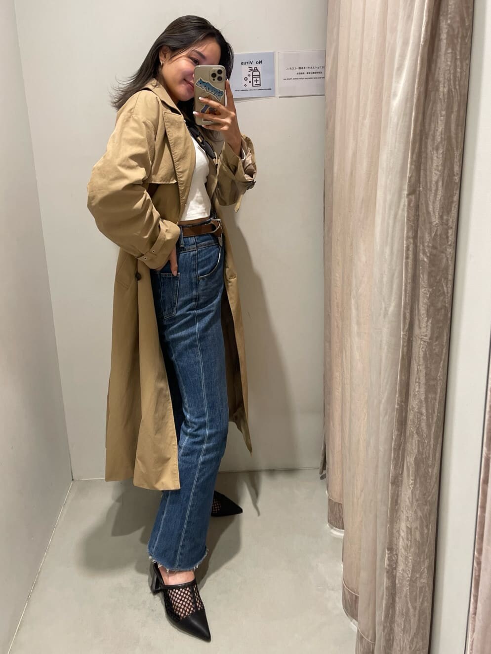 ブラック系のパンプス、ベージュ系のトレンチコート、ブルー系のデニムパンツを着用したレディースの冬コーディネートの3枚目の写真