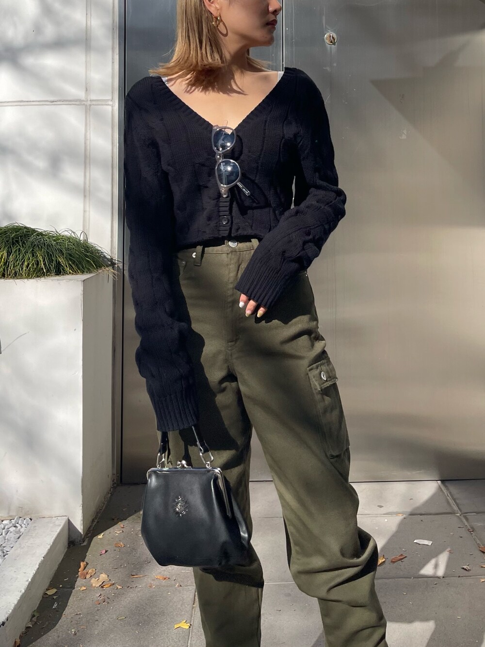 ブラック系のショルダーバッグ、ブラック系のカーディガン/ボレロ、ホワイト系のブーツを着用したレディースの冬コーディネートの3枚目の写真