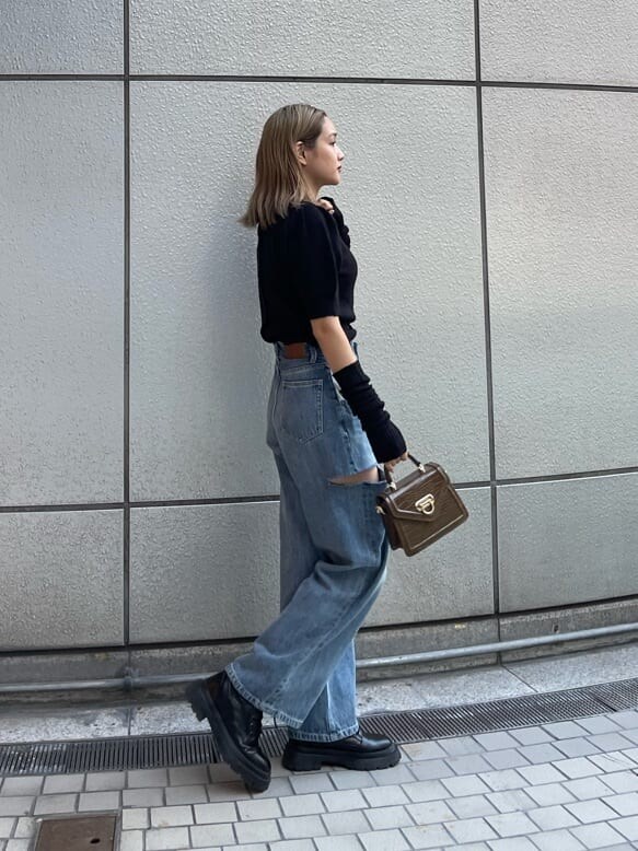 ブラック系のブーツ、ブラック系のニット/セーター、ブルー系のデニムパンツを着用したレディースの秋コーディネートの4枚目の写真