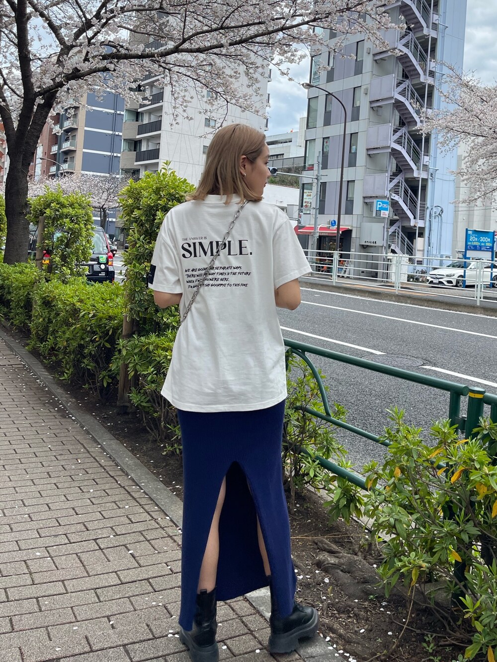 ブラック系のショルダーバッグ、ホワイト系のTシャツ/カットソー、ブルー系のスカートを着用したレディースの春コーディネートの3枚目の写真