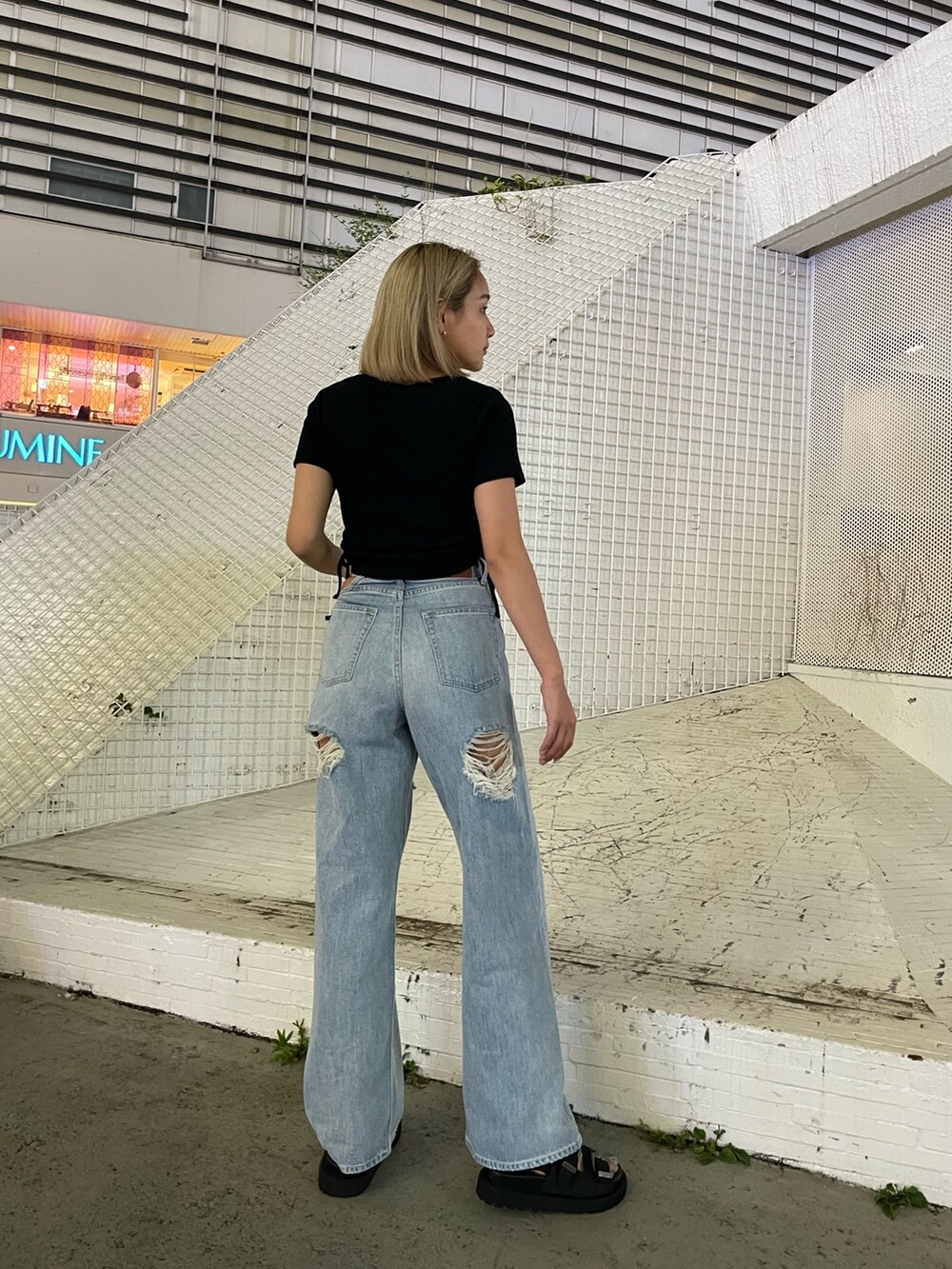 ブルー系のデニムパンツ、ブラック系のTシャツ/カットソー、ブラック系のサンダルを着用したレディースの夏コーディネートの4枚目の写真