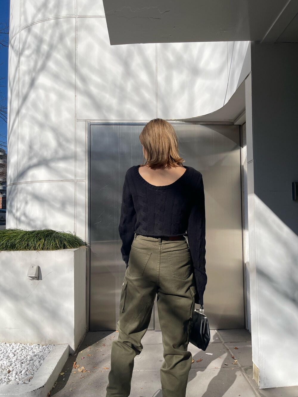 ブラック系のカーディガン/ボレロ、ブラック系のショルダーバッグ、ホワイト系のブーツを着用したレディースの冬コーディネートの5枚目の写真