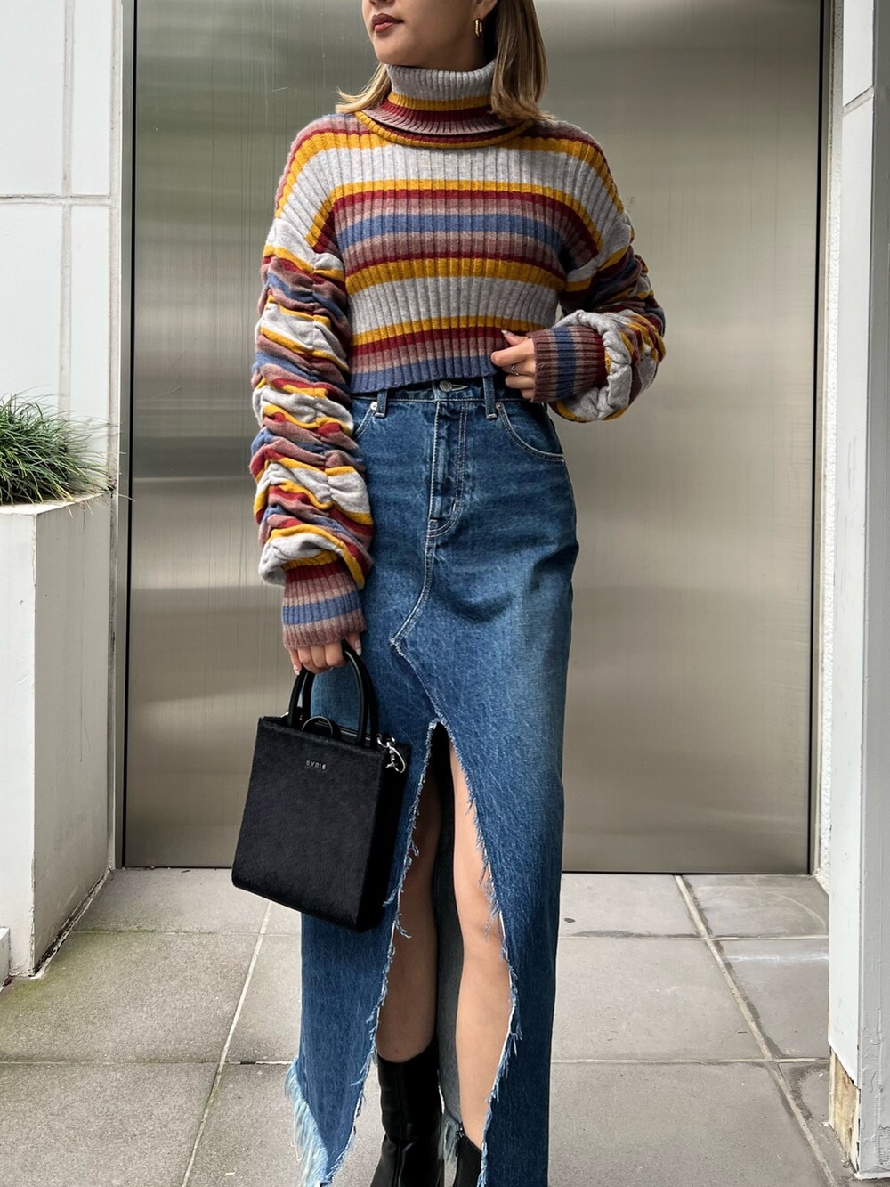 ブルー系のデニムスカート、その他のニット/セーター、ブラック系のブーツを着用したレディースの秋コーディネートの4枚目の写真