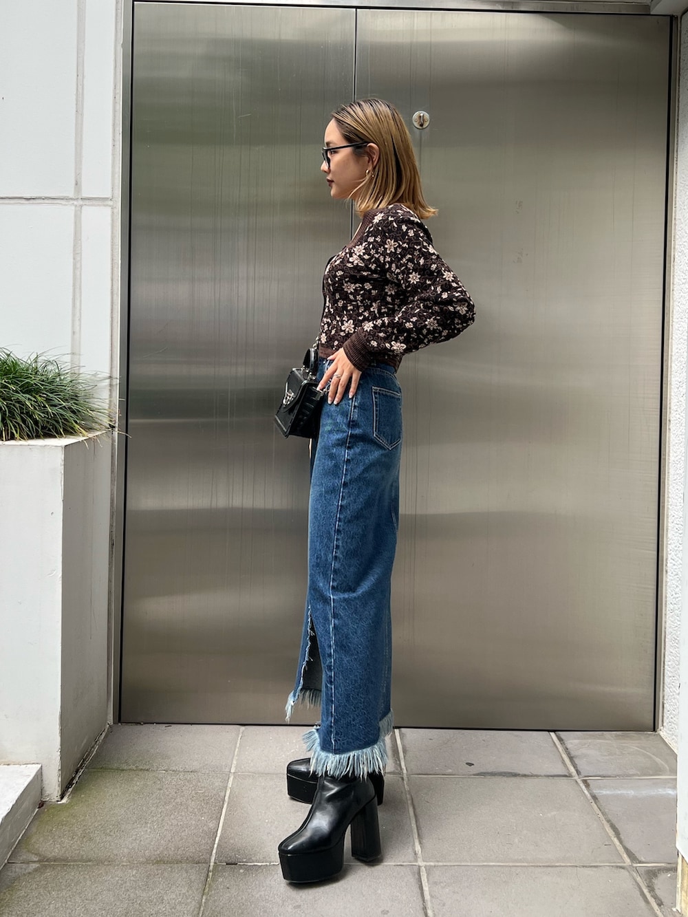 ブルー系のデニムスカート、ブラック系のブーツ、ブラック系のニット/セーターを着用したレディースの秋コーディネートの2枚目の写真