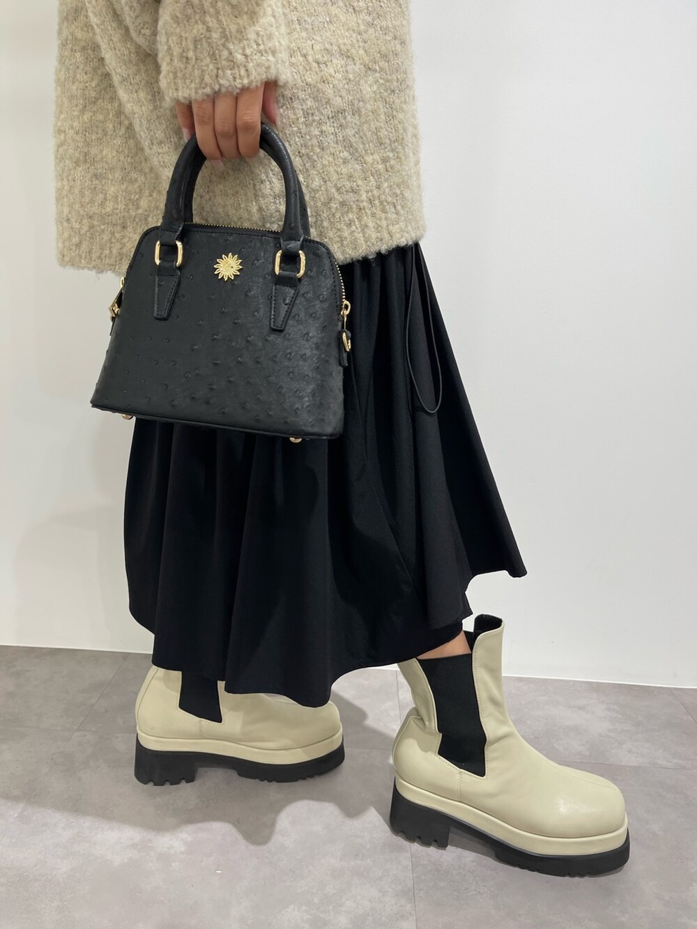 ブラック系のスカート、ホワイト系のブーツ、ブラック系のショルダーバッグを着用したレディースの秋コーディネートの8枚目の写真