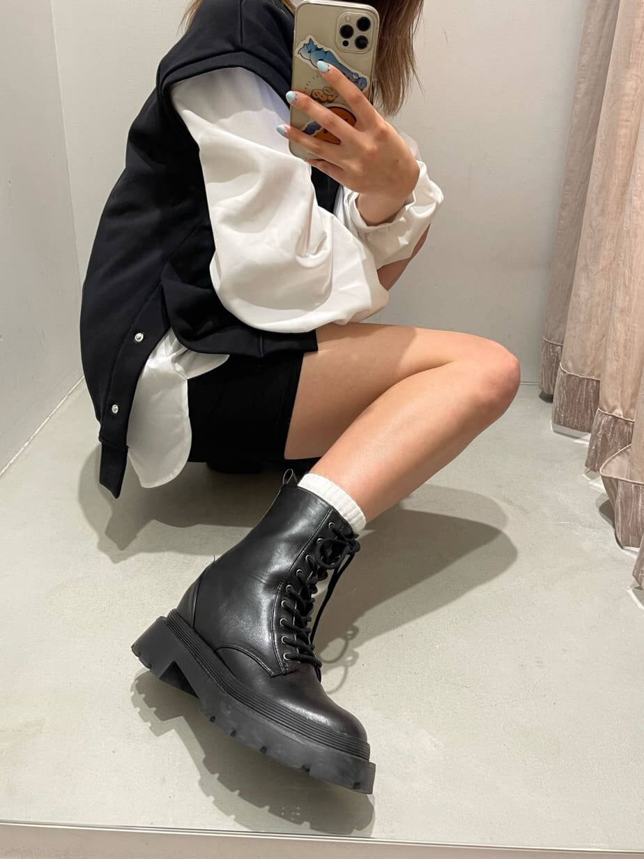 ホワイト系のシャツ/ブラウス、ブラック系のブーツ、ブラック系のベストを着用したレディースの春コーディネートの7枚目の写真