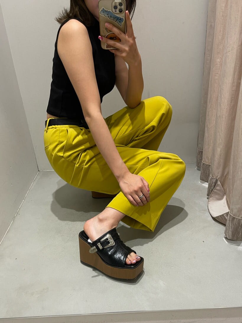 イエロー系のスラックス、ブラック系のタンクトップ、ブラック系のサンダルを着用したレディースの春コーディネートの7枚目の写真