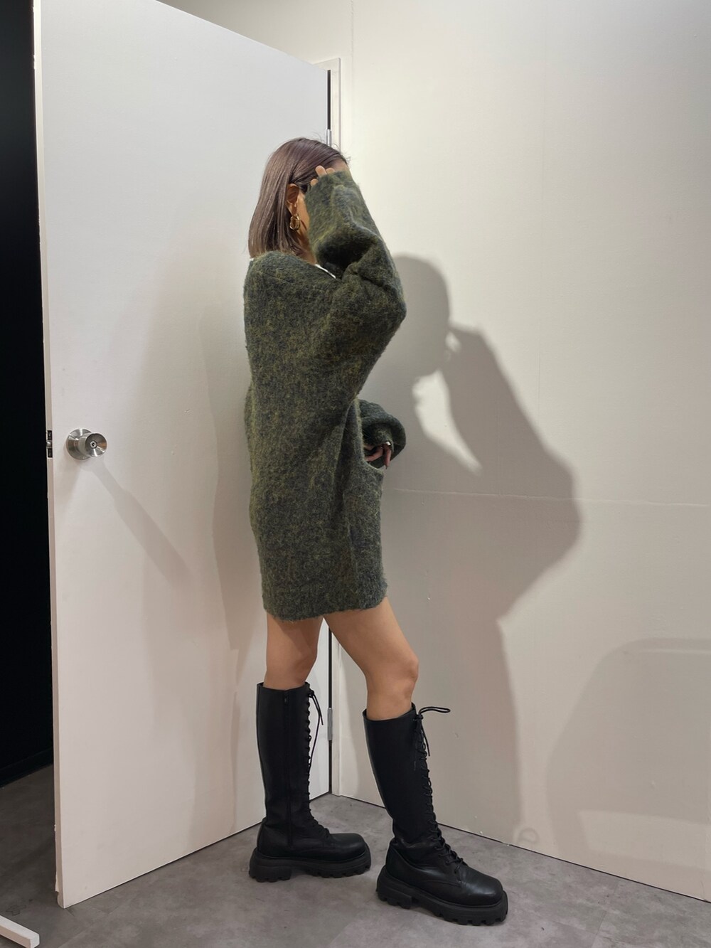 グリーン系のカーディガン/ボレロ、ブラック系のブーツ、ゴールド系のピアス（両耳用）を着用したレディースの秋コーディネートの4枚目の写真