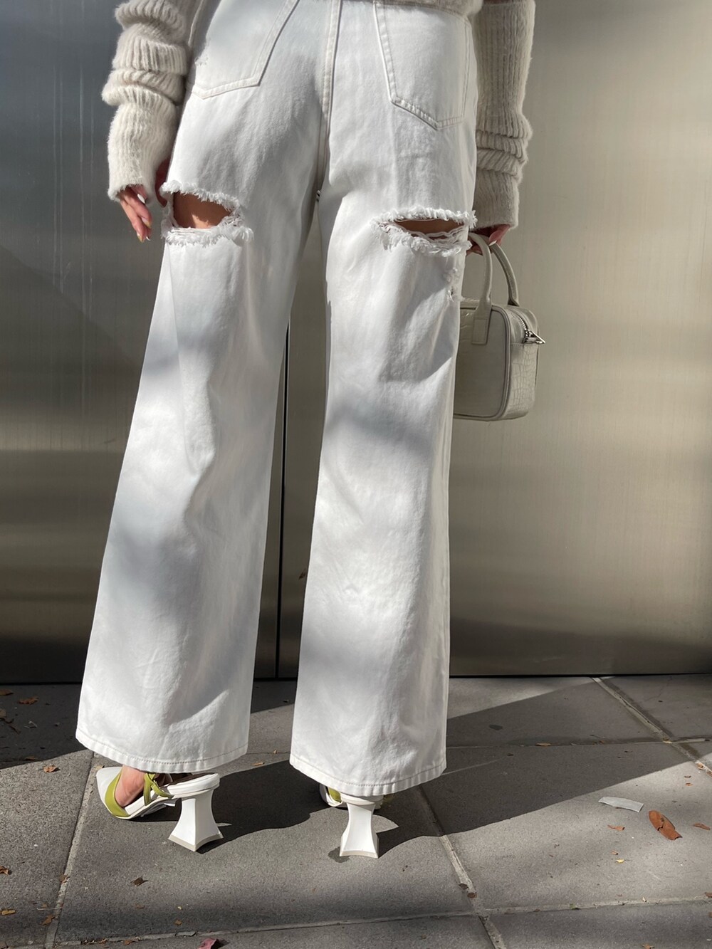 パープル系のニット/セーター、ホワイト系のデニムパンツ、ホワイト系のショルダーバッグを着用したレディースの冬コーディネートの7枚目の写真