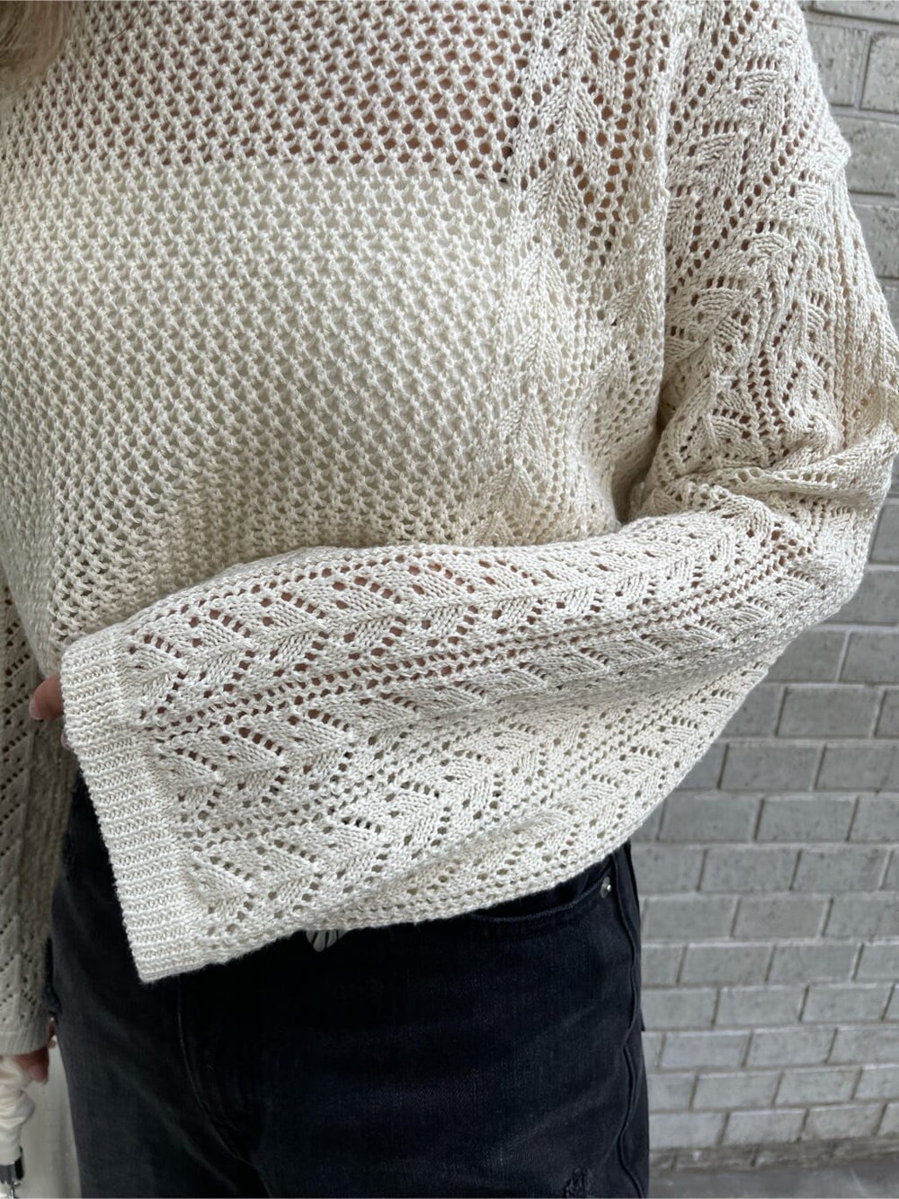 ホワイト系のキャミソール、ブラック系のデニムパンツ、ホワイト系のニット/セーターを着用したレディースの春コーディネートの6枚目の写真