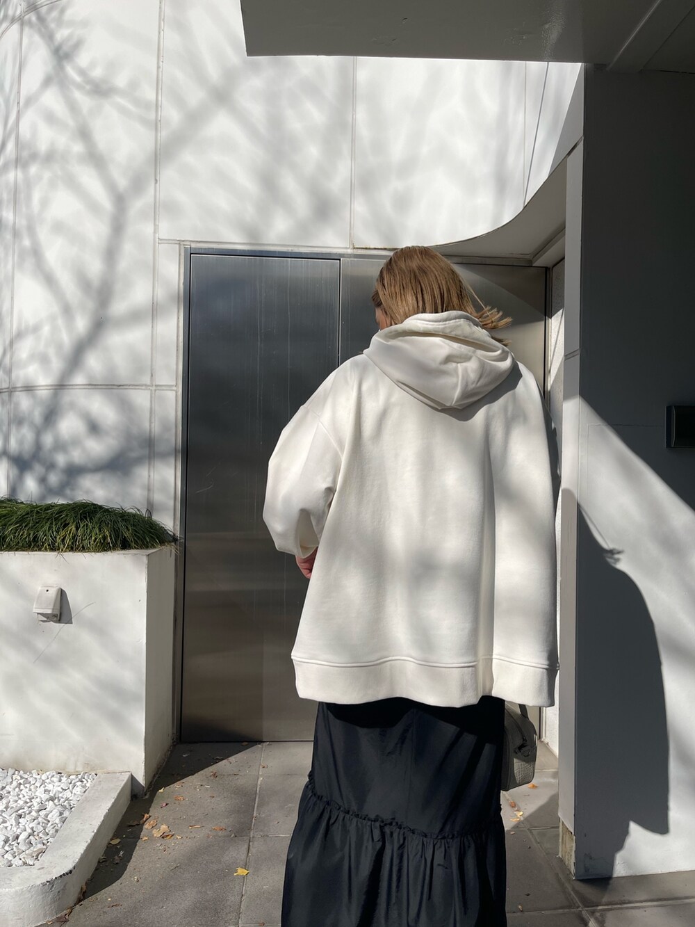 ホワイト系のパーカー、ホワイト系のショルダーバッグ、ブラック系のブーツを着用したレディースの冬コーディネートの4枚目の写真