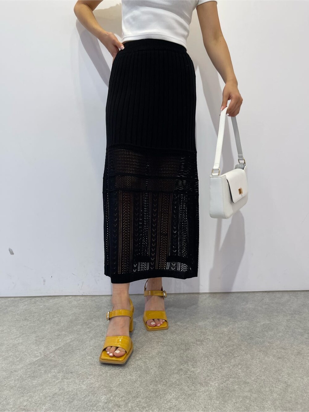 イエロー系のサンダル、ホワイト系のショルダーバッグ、ブラック系のスカートを着用したレディースの夏コーディネートの5枚目の写真