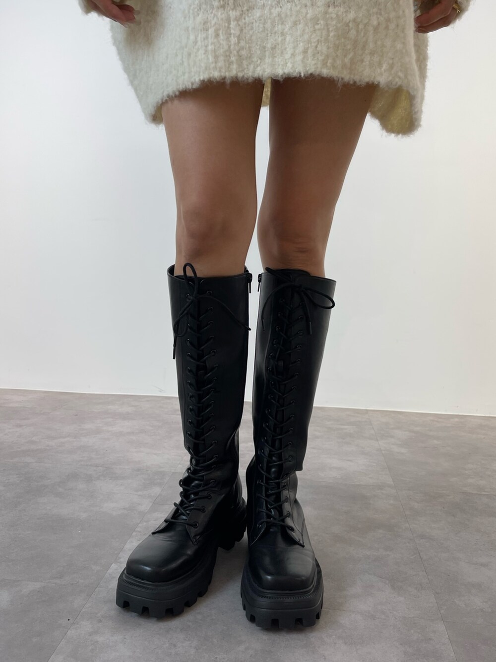 レッド系のニット/セーター、ブラック系のブーツ、ホワイト系のショルダーバッグを着用したレディースの秋コーディネートの7枚目の写真