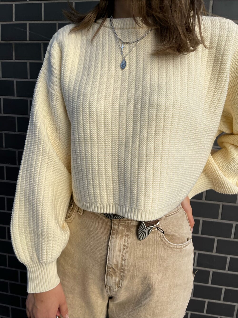 ベージュ系のデニムパンツ、ブラウン系のショルダーバッグ、ホワイト系のニット/セーターを着用したレディースの冬コーディネートの3枚目の写真