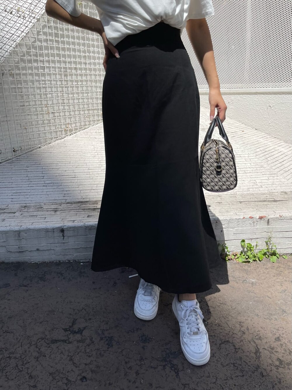 ブラック系のスカート、ブラック系のボストンバッグ、ホワイト系のTシャツ/カットソーを着用したレディースの夏コーディネートの6枚目の写真