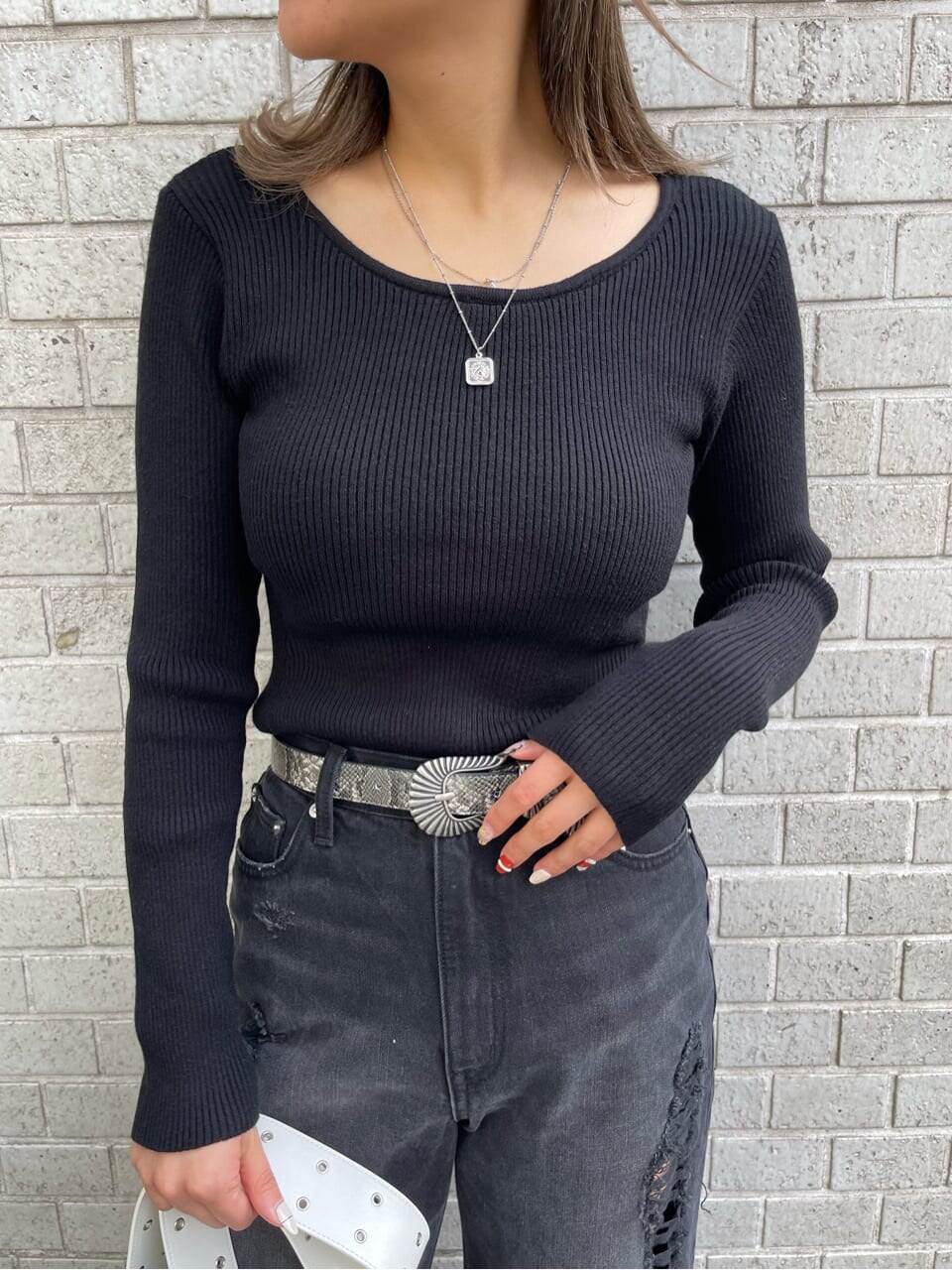 ブラック系のデニムパンツ、ブラック系のニット/セーター、ホワイト系のショルダーバッグを着用したレディースの冬コーディネートの7枚目の写真