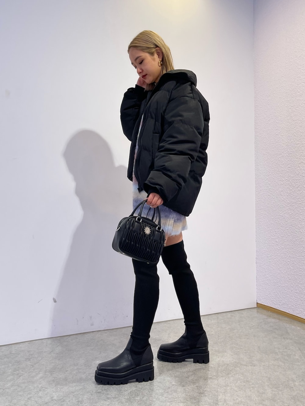 パープル系のニット/セーター、ブラック系のブーツ、ブラック系のダウンジャケット/コートを着用したレディースの冬コーディネートの4枚目の写真