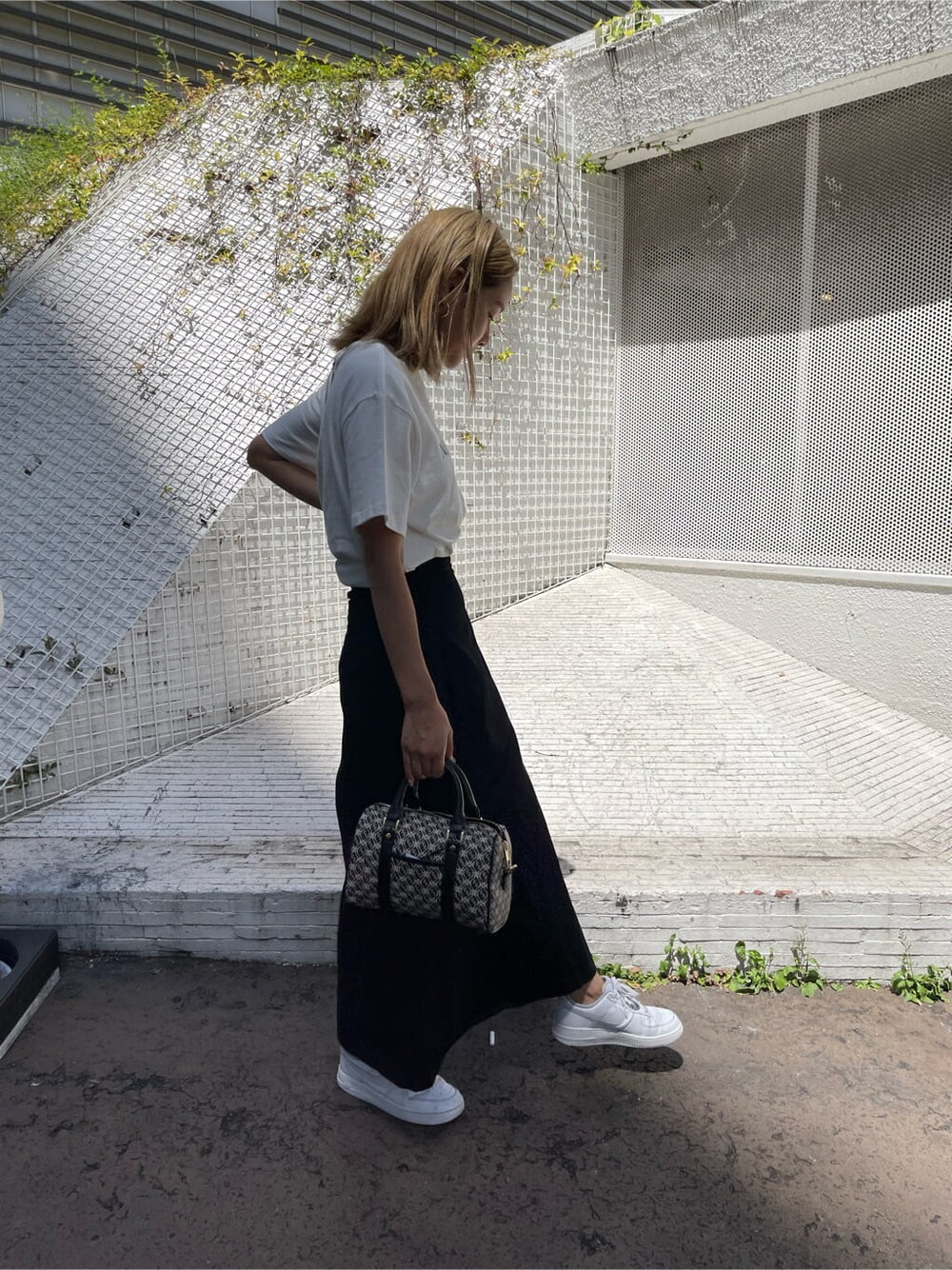 ブラック系のスカート、ブラック系のボストンバッグ、ホワイト系のTシャツ/カットソーを着用したレディースの夏コーディネートの4枚目の写真