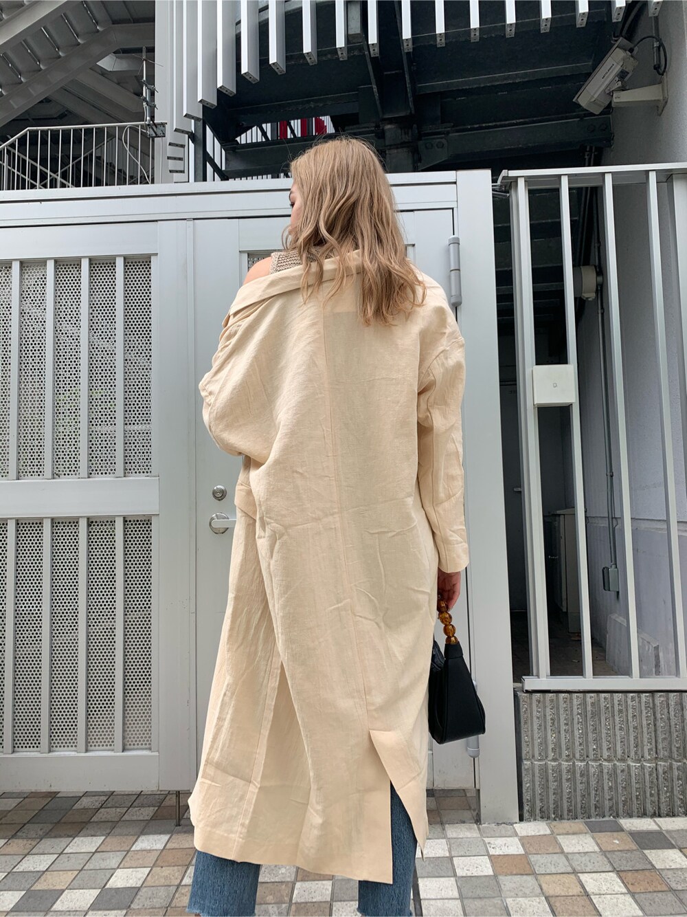 ブルー系のデニムパンツ、ブラック系のサンダル、ベージュ系のチェスターコートを着用したレディースの春コーディネートの6枚目の写真