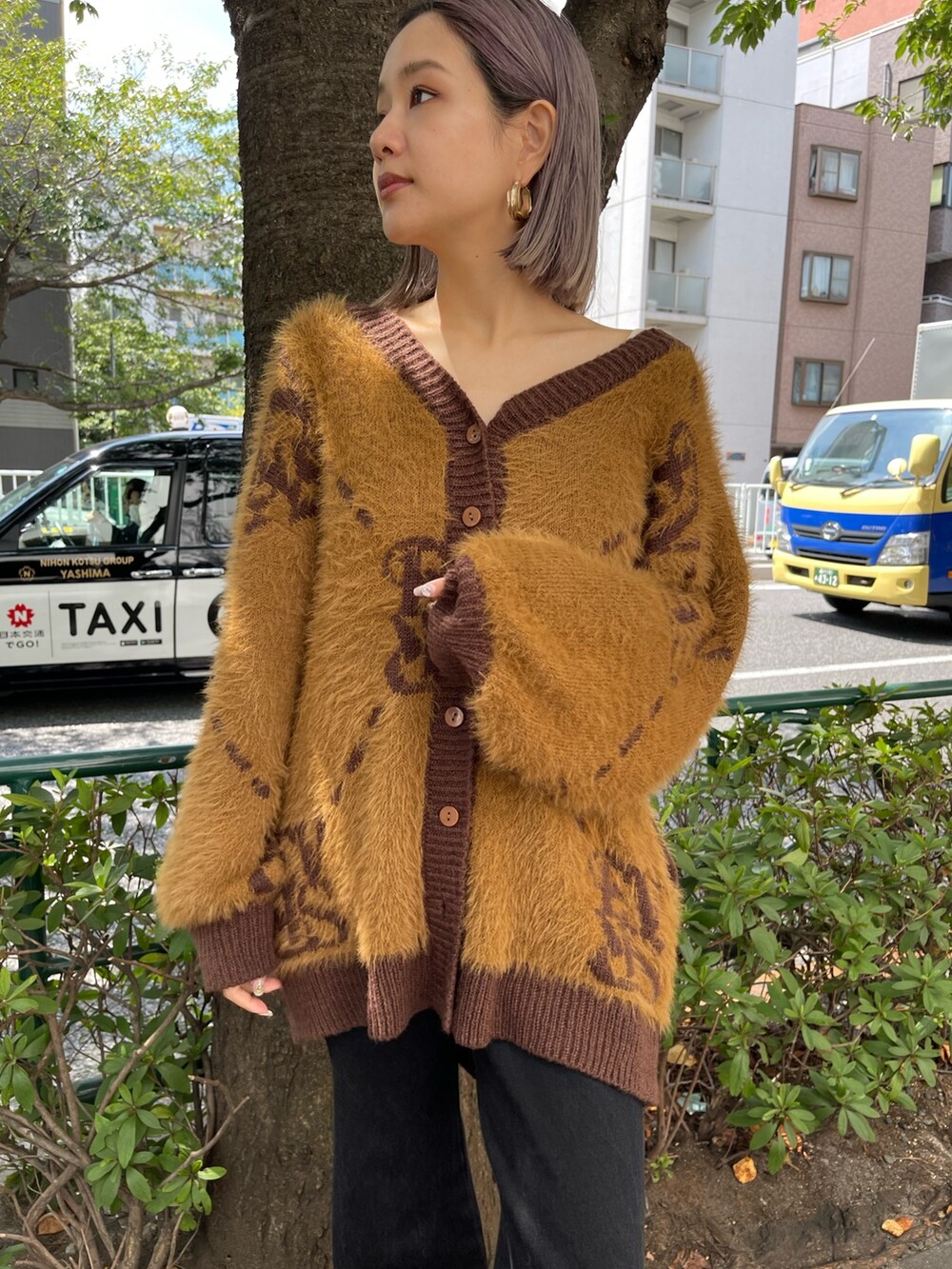 ブラック系のデニムパンツ、ブラウン系のカーディガン/ボレロ、ゴールド系のピアス（両耳用）を着用したレディースの秋コーディネートの5枚目の写真