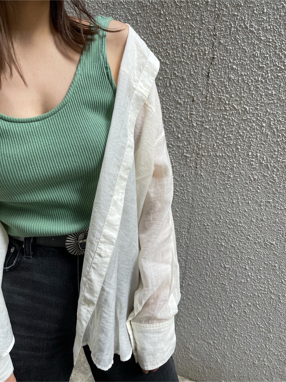 ブラック系のデニムパンツ、ホワイト系のシャツ/ブラウス、グリーン系のタンクトップを着用したレディースの春コーディネートの6枚目の写真