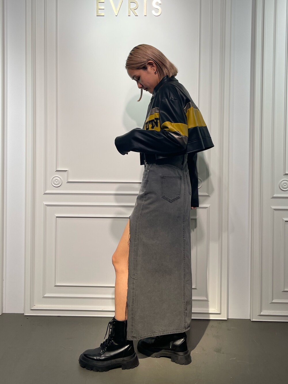 ブラック系のデニムスカート、ブラック系のブーツ、ホワイト系のTシャツ/カットソーを着用したレディースの夏コーディネートの3枚目の写真