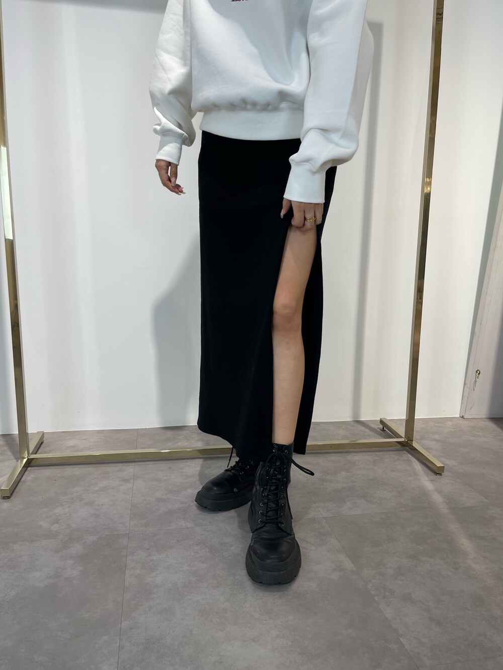 ブラック系のスカート、ブラック系のブーツ、ホワイト系のスウェットを着用したレディースの秋コーディネートの5枚目の写真