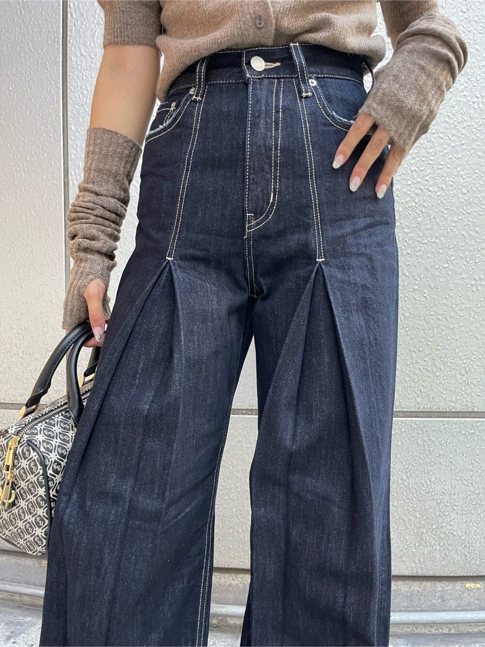 ブラック系のスリッポン、ブラック系のボストンバッグ、ブルー系のデニムパンツを着用したレディースの夏コーディネートの6枚目の写真