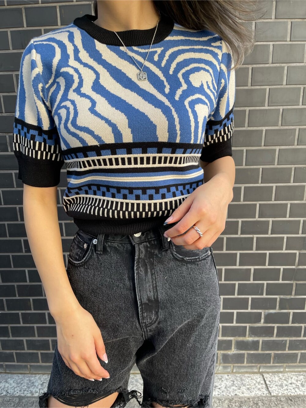 ブラック系のブーツ、ブラック系のデニムパンツ、ブルー系のニット/セーターを着用したレディースの春コーディネートの5枚目の写真