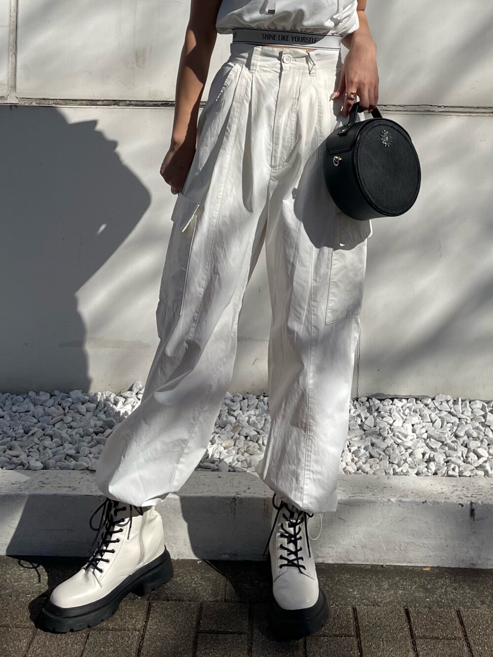 ホワイト系のブーツ、ホワイト系のカーゴパンツ、ブラック系のショルダーバッグを着用したレディースの春コーディネートの6枚目の写真