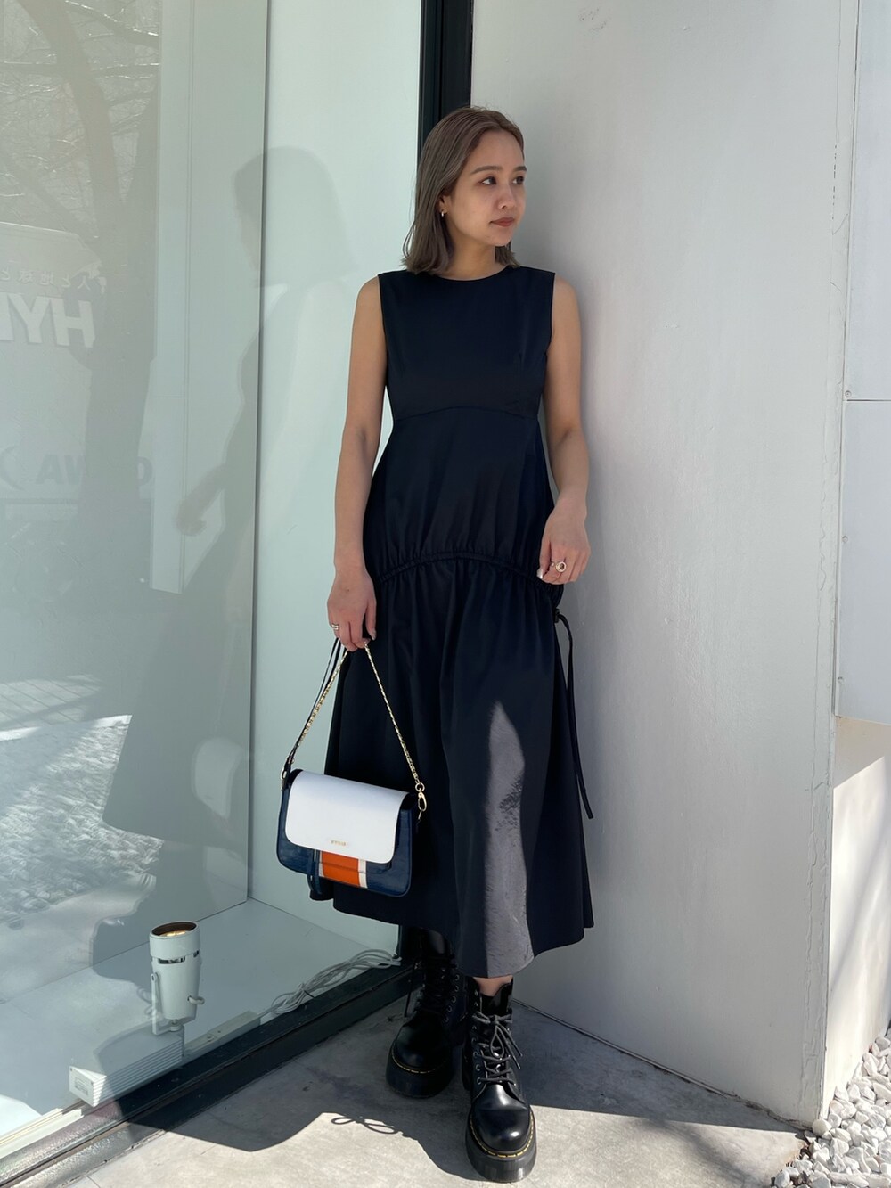 ブラック系のブーツ、ブルー系のショルダーバッグ、ブラック系のワンピースを着用したレディースの春コーディネートの2枚目の写真