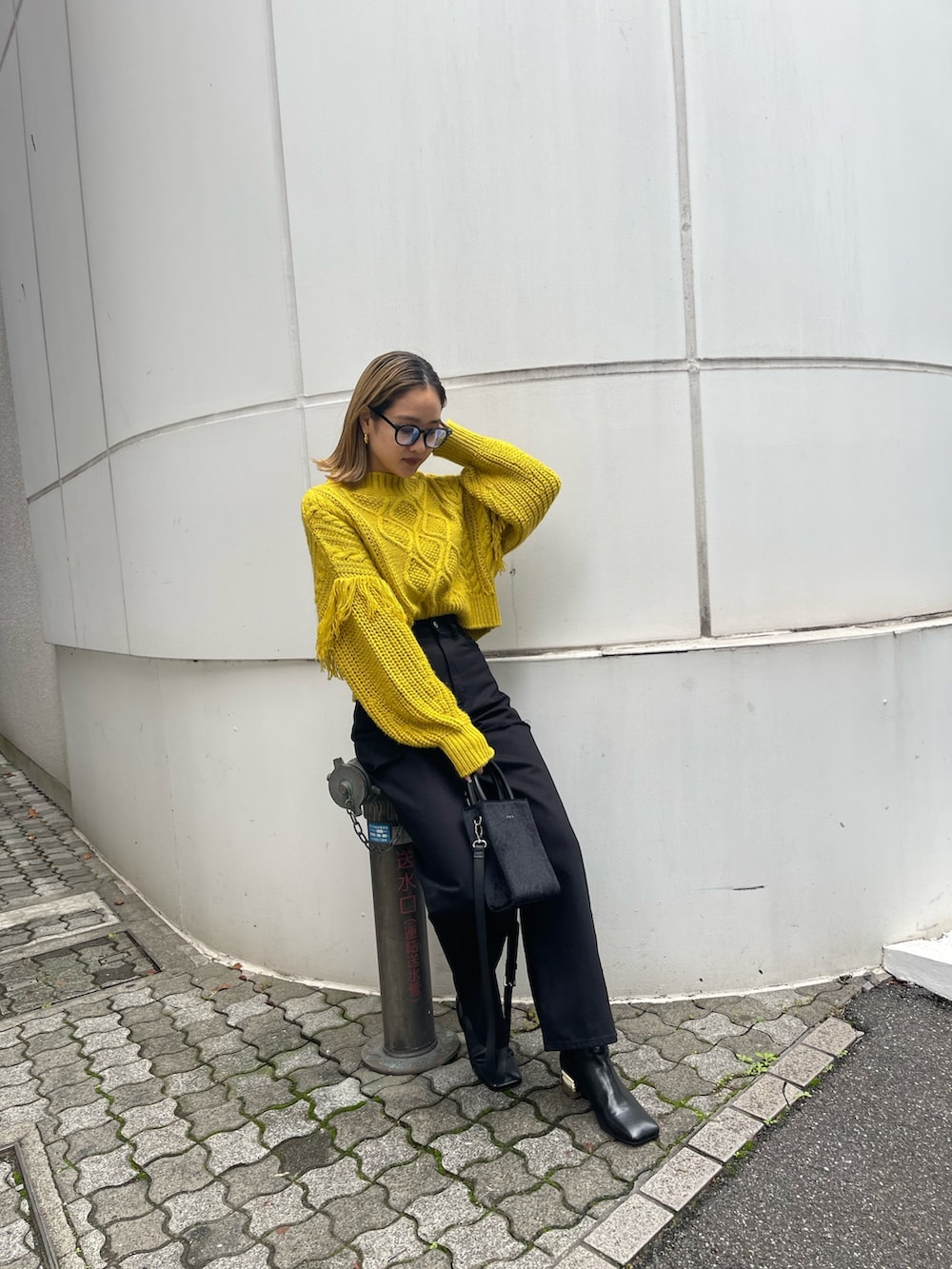 ブラック系のショルダーバッグ、イエロー系のニット/セーター、ブラック系のデニムパンツを着用したレディースの秋コーディネートの6枚目の写真