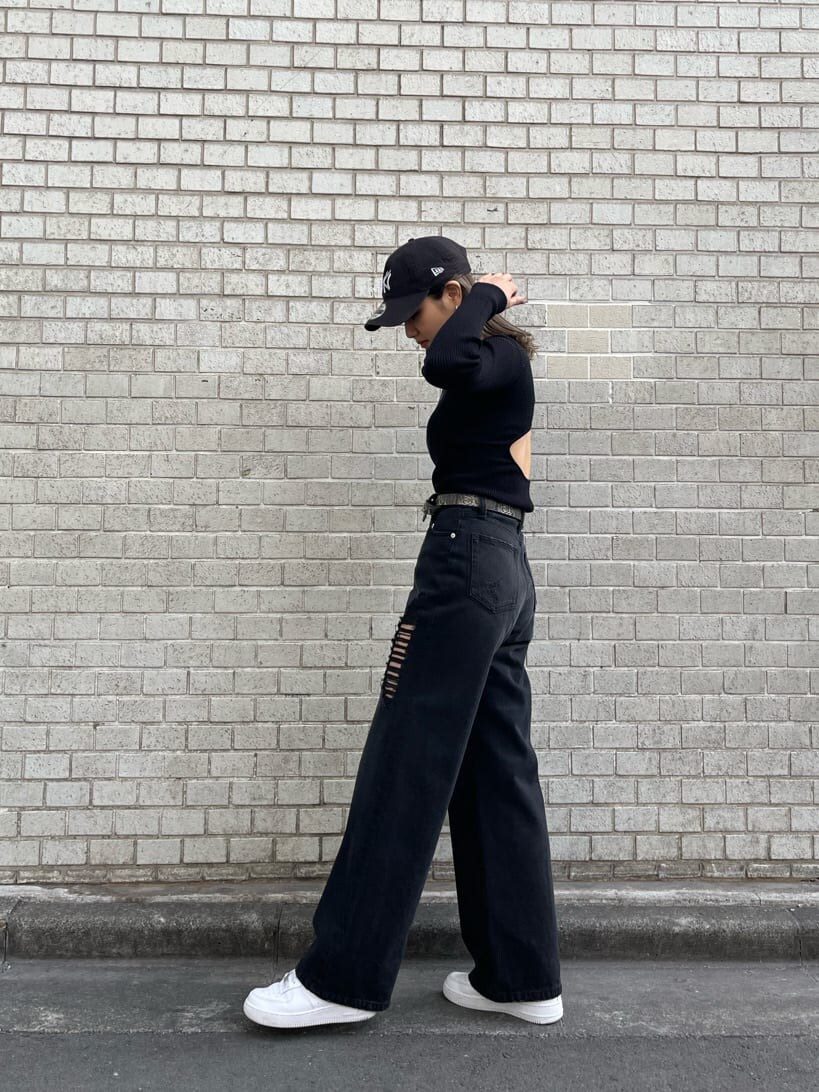 ブラック系のデニムパンツ、ブラック系のニット/セーター、ホワイト系のショルダーバッグを着用したレディースの冬コーディネートの3枚目の写真