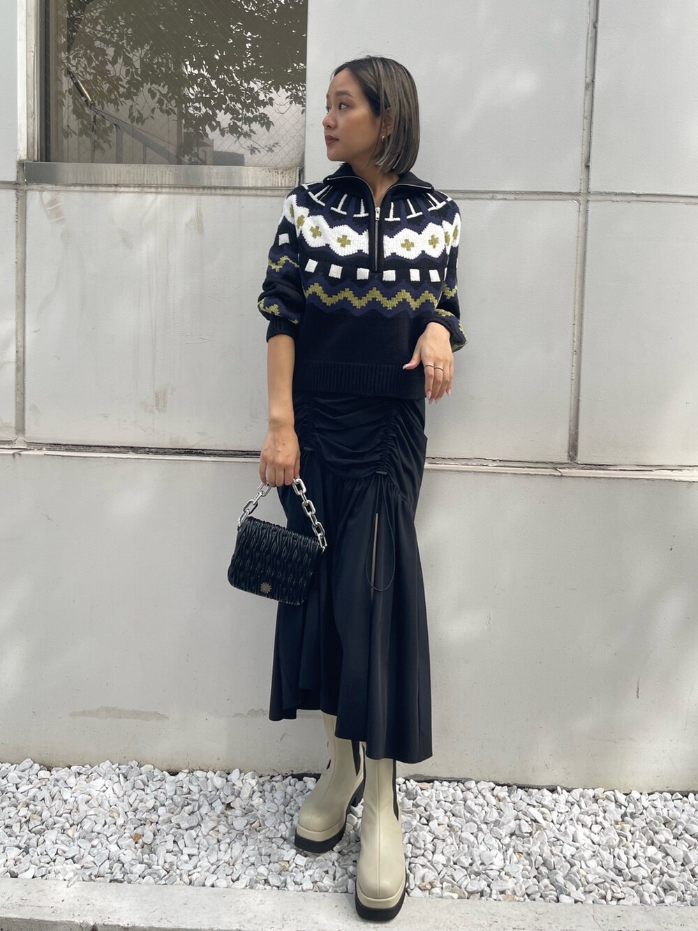 ブラック系のスカート、ホワイト系のブーツ、ブラック系のニット/セーターを着用したレディースの秋コーディネートの2枚目の写真