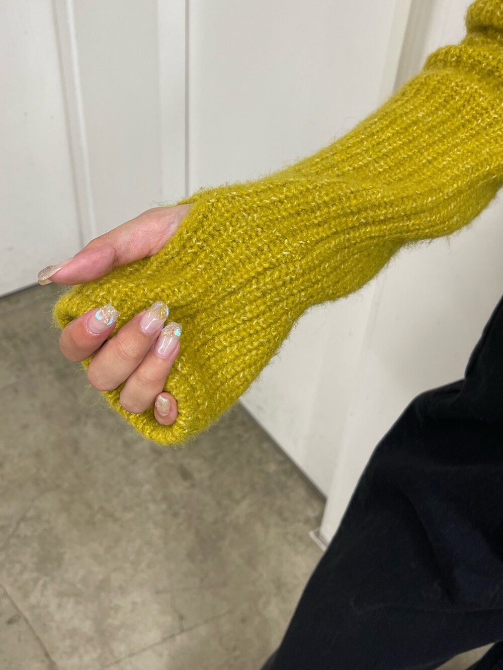 イエロー系のニット/セーター、ブラック系のデニムパンツ、ベージュ系のスリッポンを着用したレディースの秋コーディネートの7枚目の写真