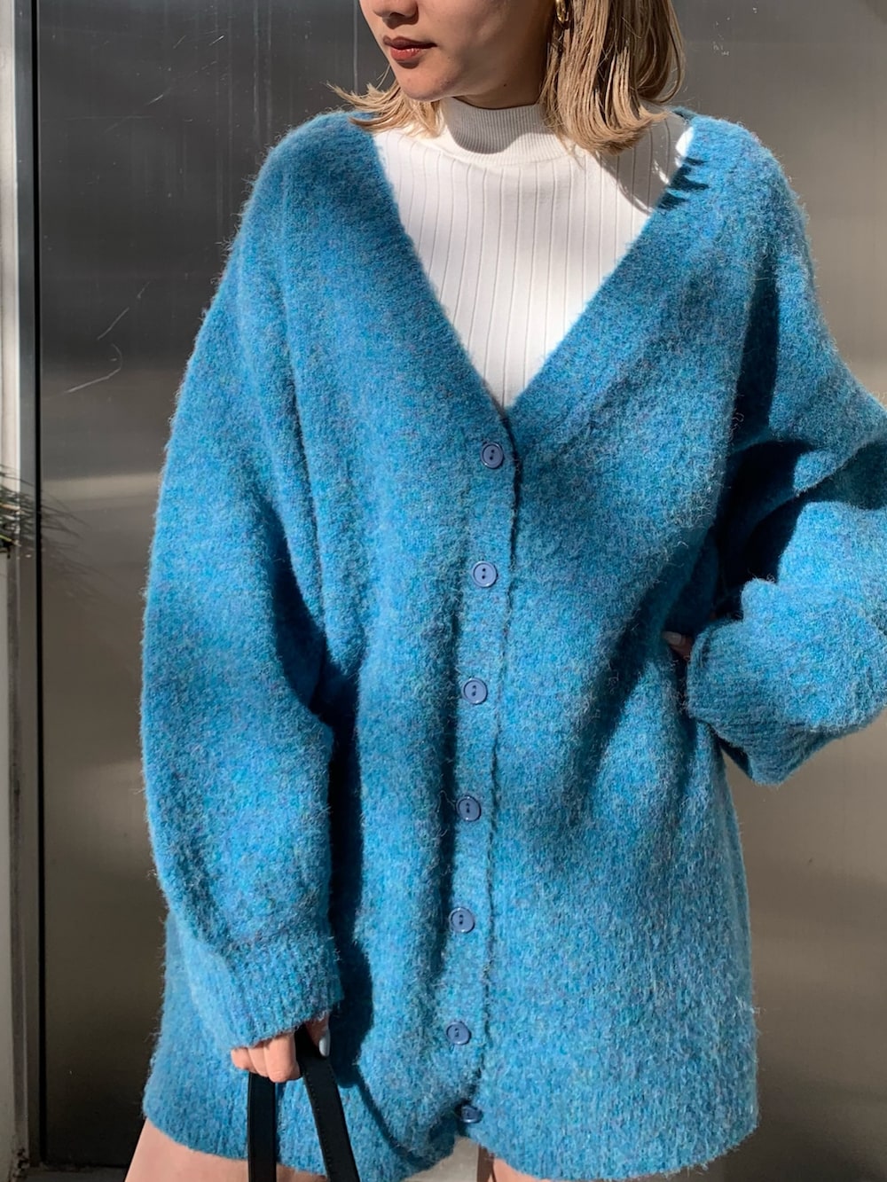 ブラック系のハンドバッグ、ブルー系のカーディガン/ボレロ、ホワイト系のTシャツ/カットソーを着用したレディースの冬コーディネートの4枚目の写真