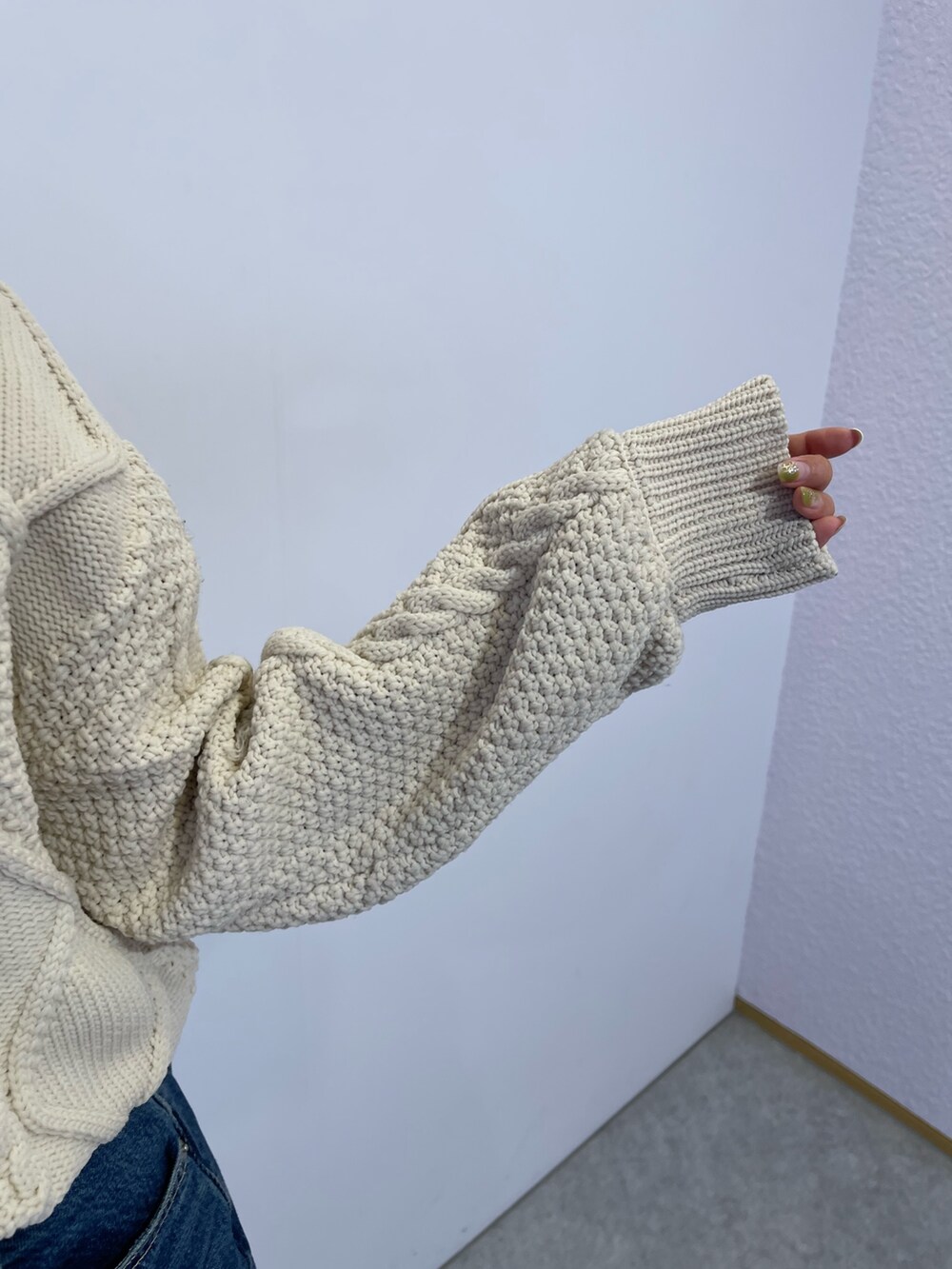 ブルー系のデニムスカート、ブラック系のブーツ、ホワイト系のニット/セーターを着用したレディースの冬コーディネートの5枚目の写真