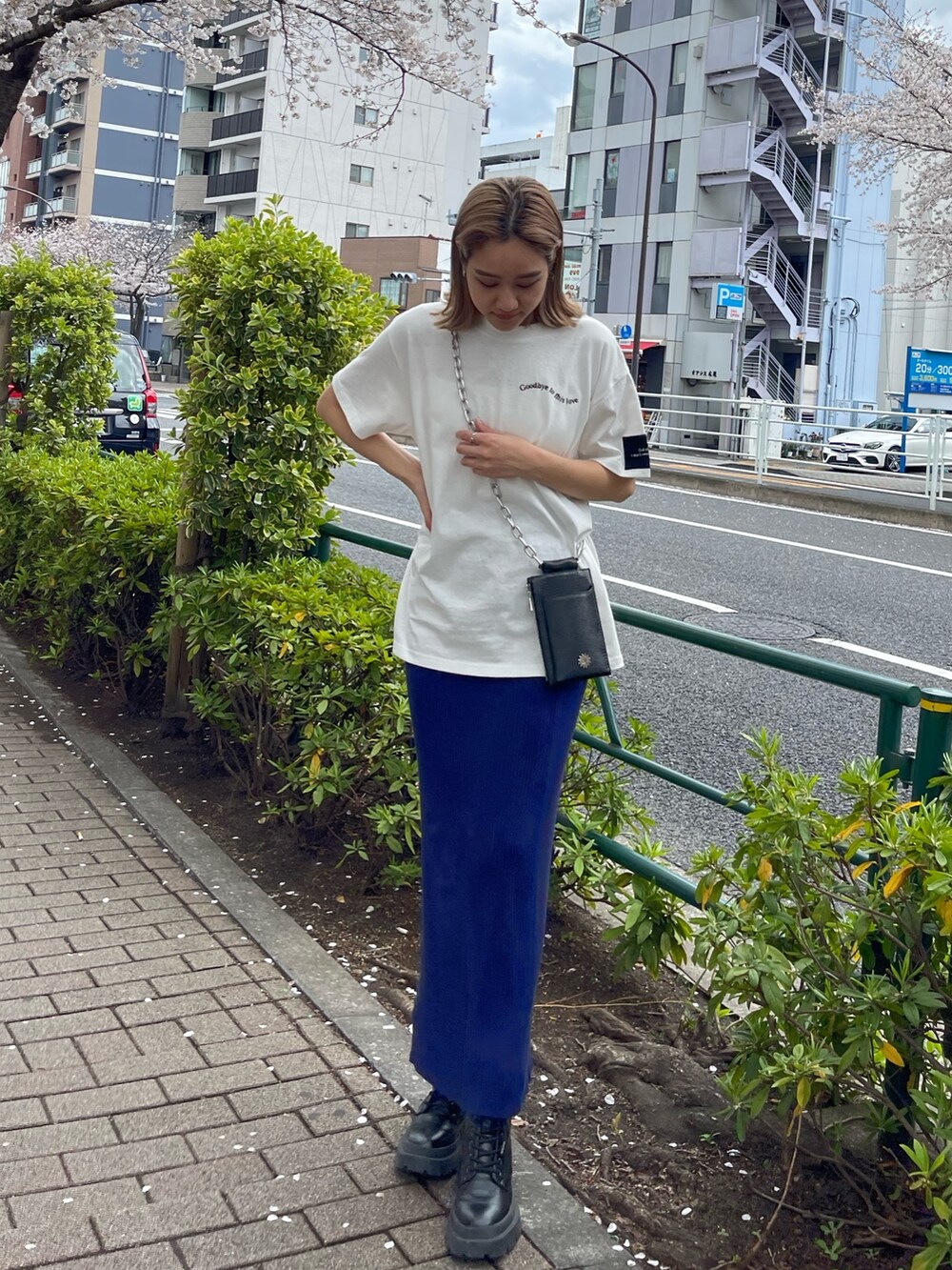 ブラック系のショルダーバッグ、ホワイト系のTシャツ/カットソー、ブルー系のスカートを着用したレディースの春コーディネートの2枚目の写真