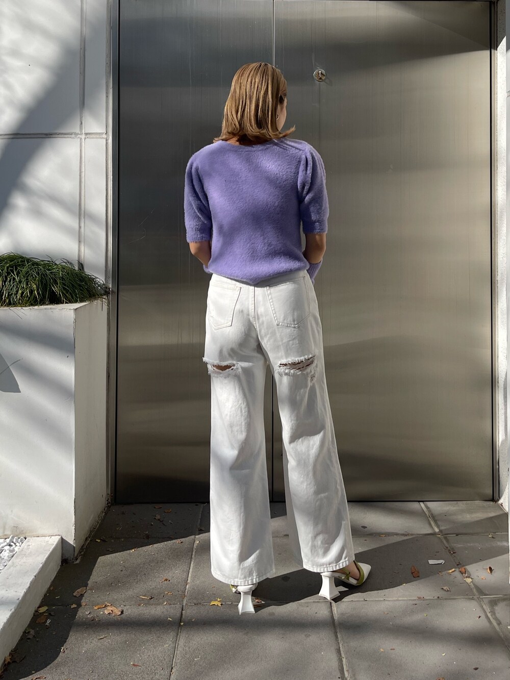 パープル系のニット/セーター、ホワイト系のデニムパンツ、ホワイト系のショルダーバッグを着用したレディースの冬コーディネートの4枚目の写真